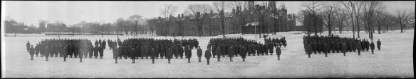 Photographie panoramique en noir et blanc présentant quatre groupes de soldats se tenant debout, dehors, en hiver.