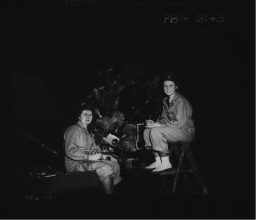 Deux femmes vêtues de combinaisons assises de part et d’autre d’une hélice.